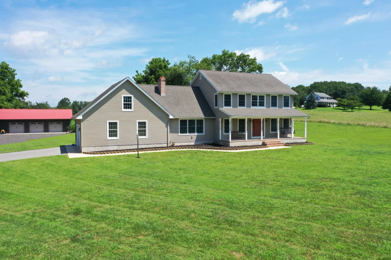 A farmhouse style home on open ground in South Jersey with a barn alongside